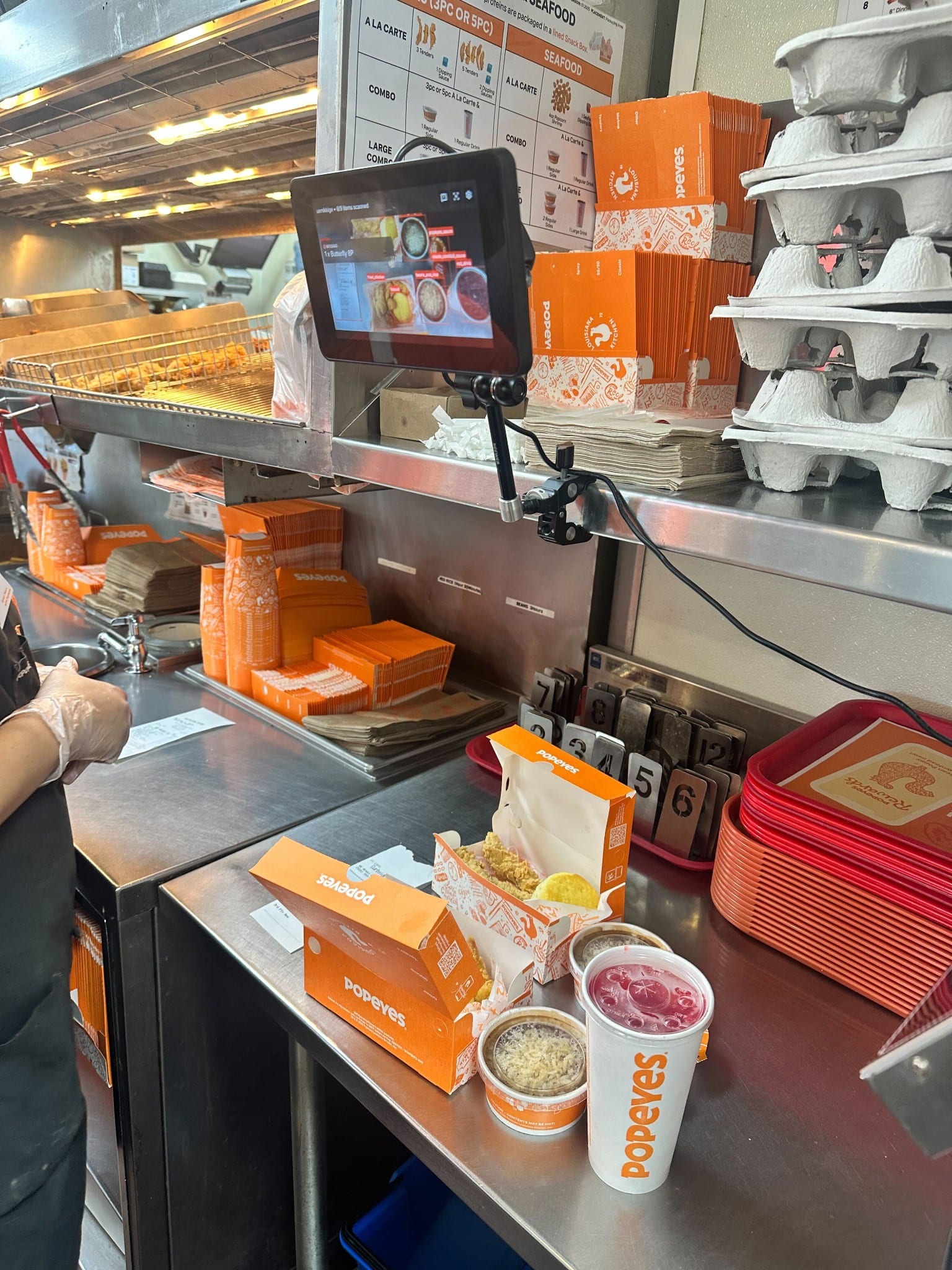Packaging counter with orange boxes and a mounted tablet.