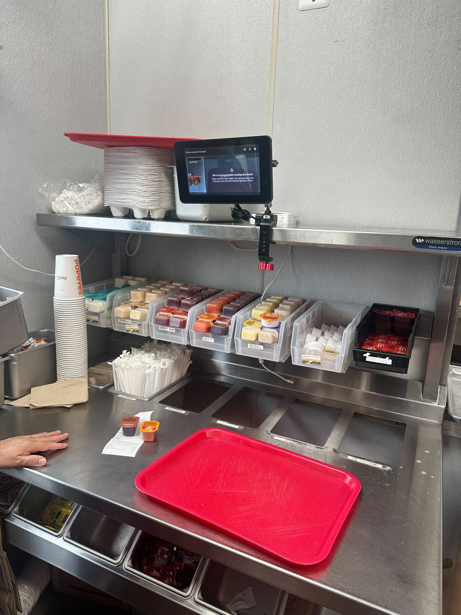 Sauce station with a mounted tablet and a red tray.